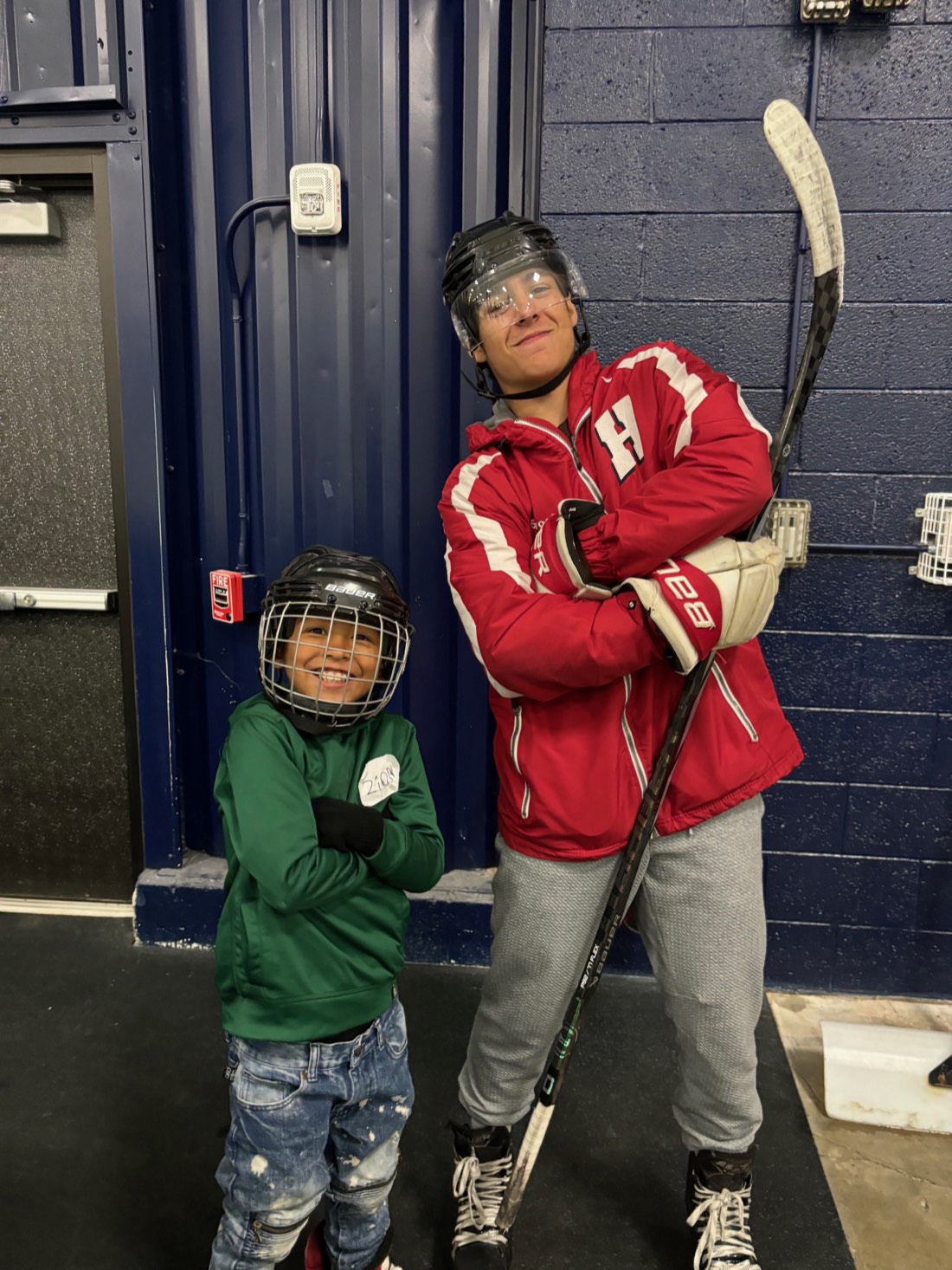 A young Break the Ice participant with a volunteer mentor in hockey gear at the rink